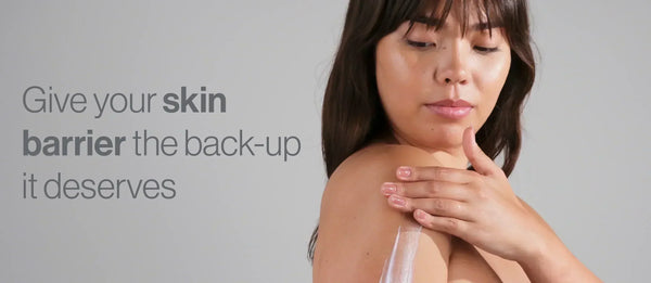 Woman applying cream to her shoulder against a soft grey background, with text reading “Give your skin barrier the back-up it deserves”.