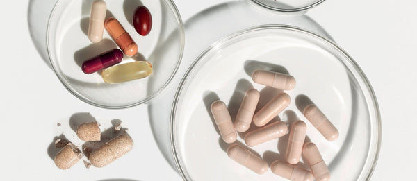 Assorted Advanced Nutrition Programme capsules displayed in glass dishes on a white surface, highlighting daily wellness and nutritional support.