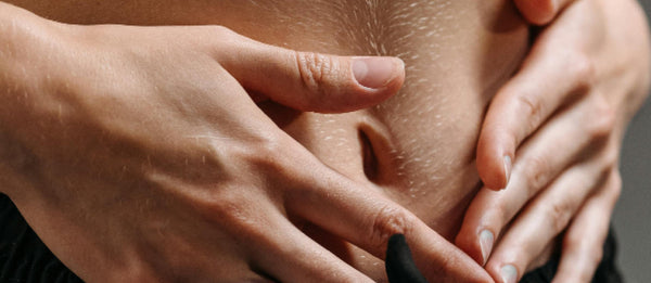 Close-up of hands resting gently over the stomach, representing gut health and the microbiome.